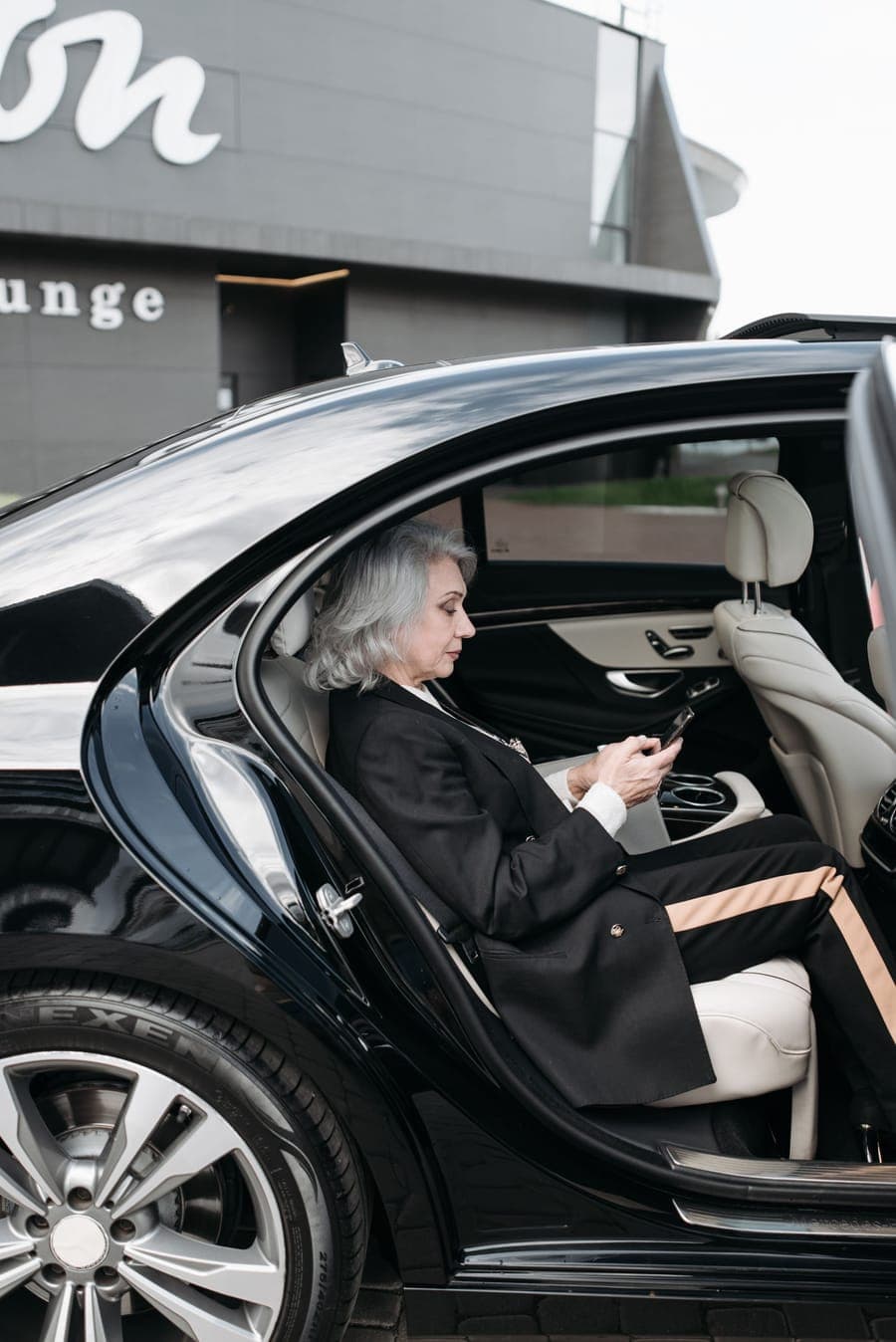 A chauffeur holding the car door for a business passenger